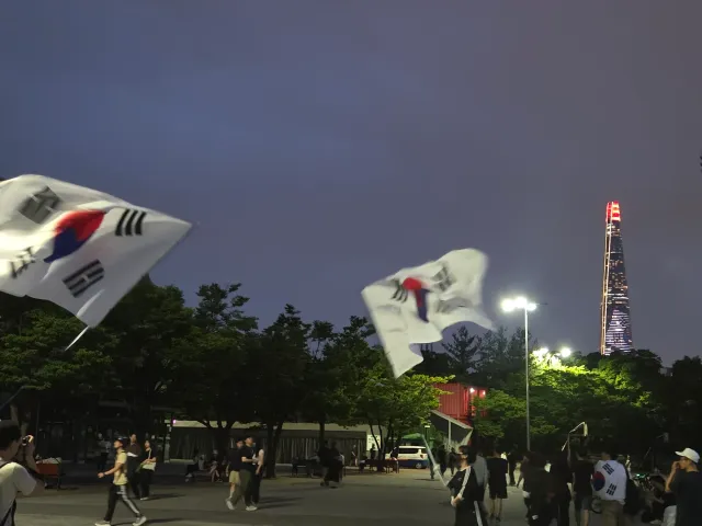 본인 몸만한 대형 태극기를 휘날려주시는 여성분과 롯데타워의 태극기